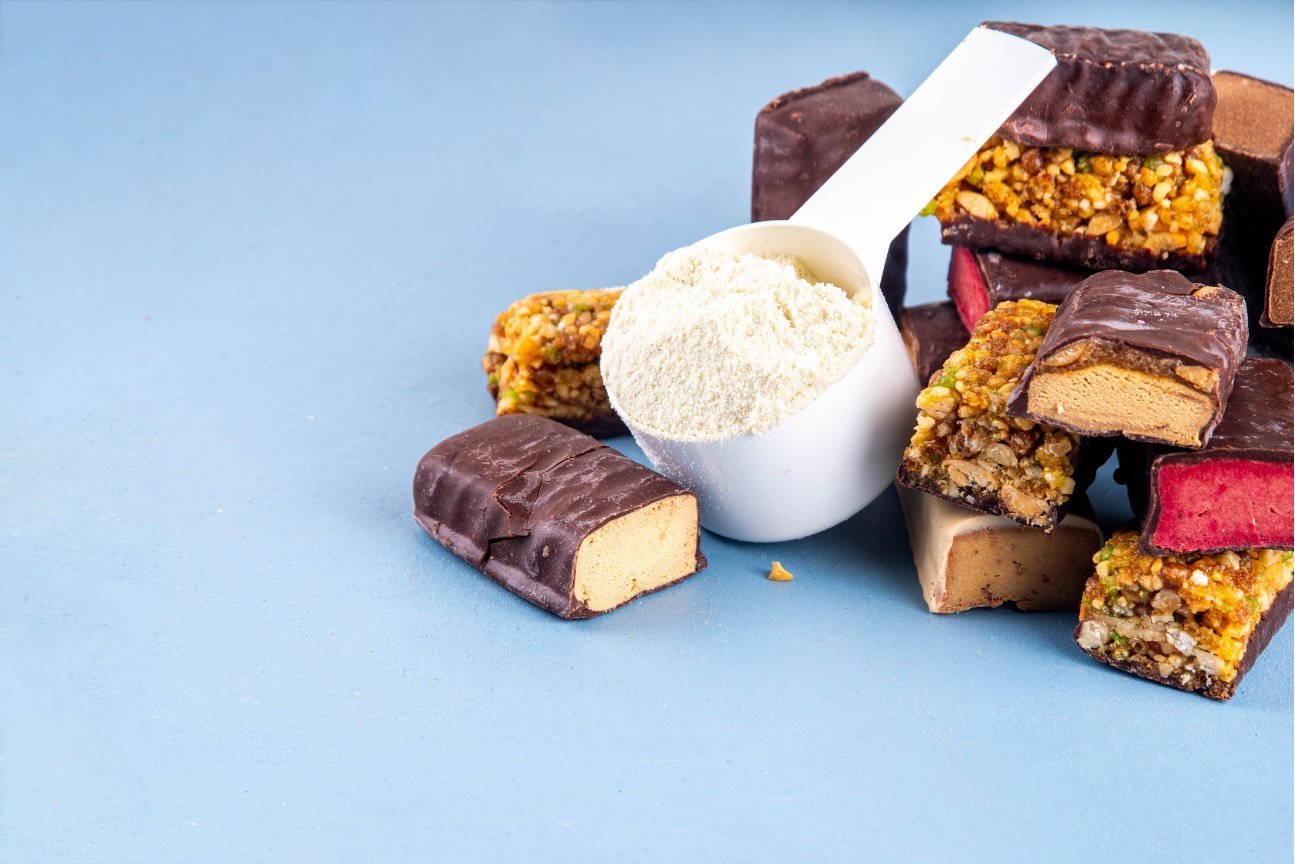 Healthy protein bars and a scoop of protein powder on a blue background