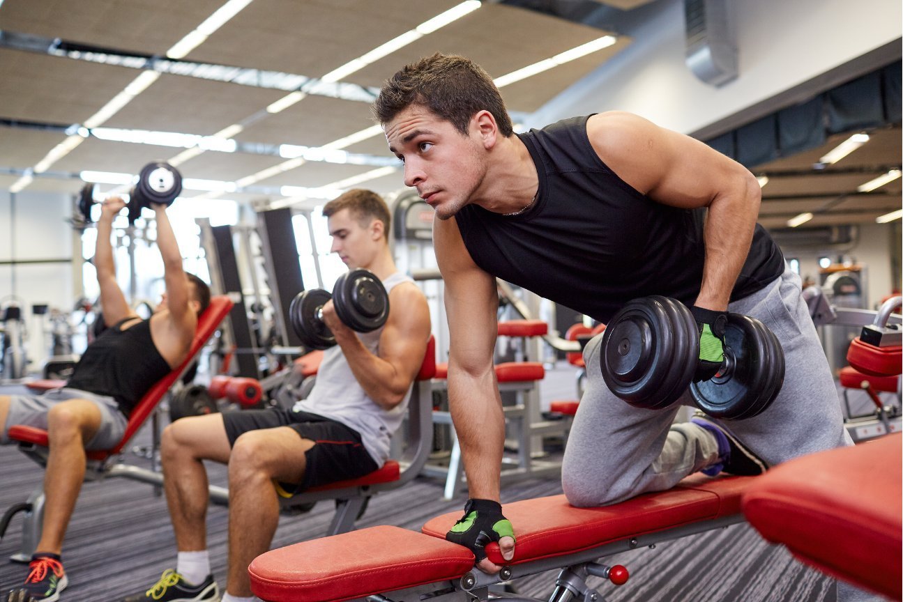 Men training with dumbbells in a commercial gym